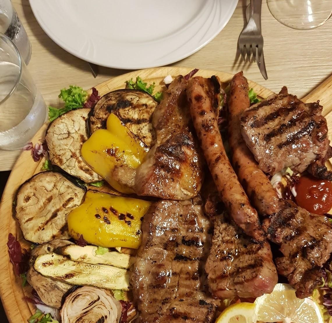 Grigliata mista con salsiccia, costine e verdure alla griglia sul tagliere